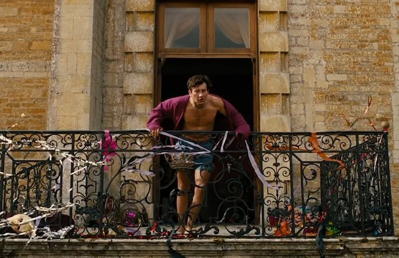 A man stands on a balcony, adorned with streamers and confetti
