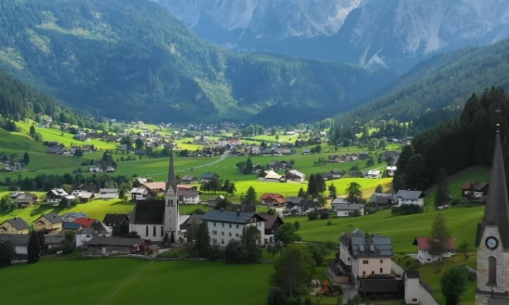 A picturesque Austrian mountain village surrounded by lush green grass and trees