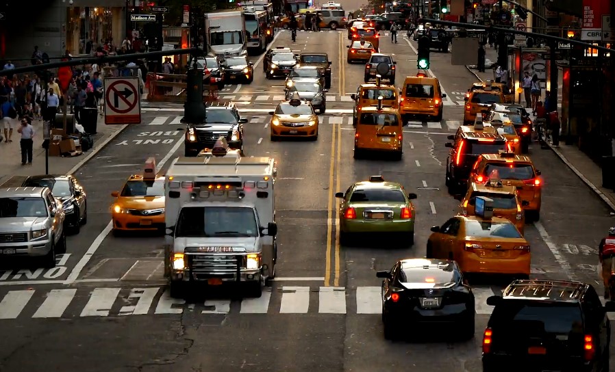 A bustling city street filled with numerous cars and taxis navigating through traffic