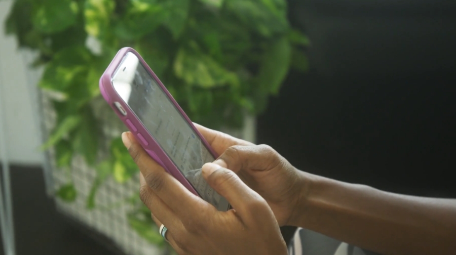 A person holds a smartphone with a purple case, focusing on safe daily use to avoid hacking