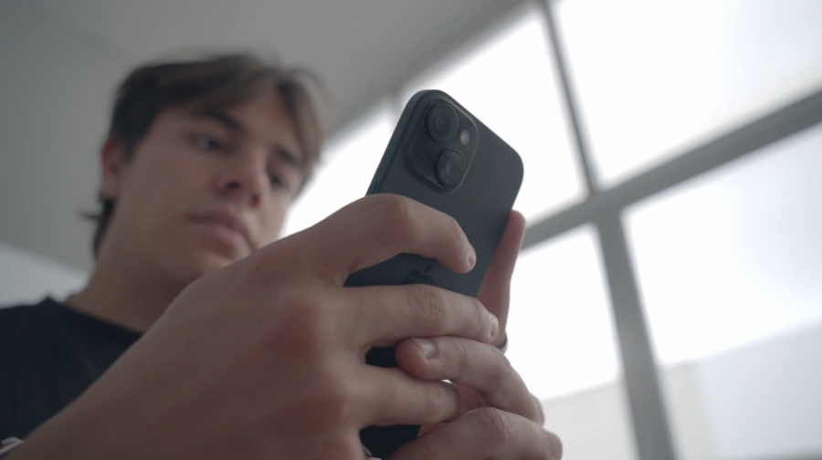 A man looks at his iPhone closely, checking for signs of a possible hack or security issue