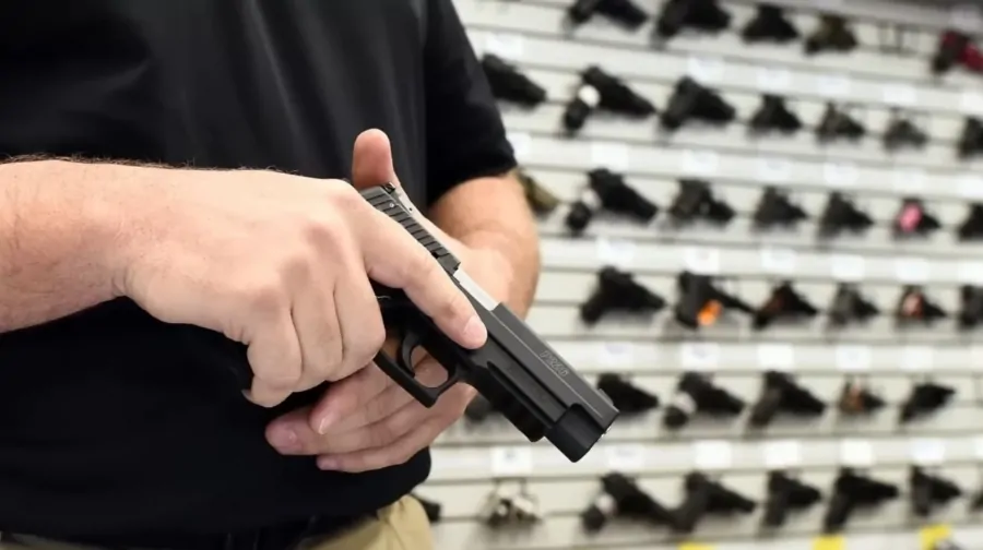 A man examines a handgun in a gun store