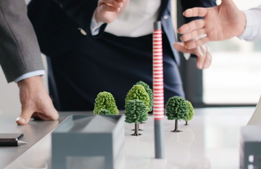 A model of a power plant, complete with miniature trees, is being examined by professionals