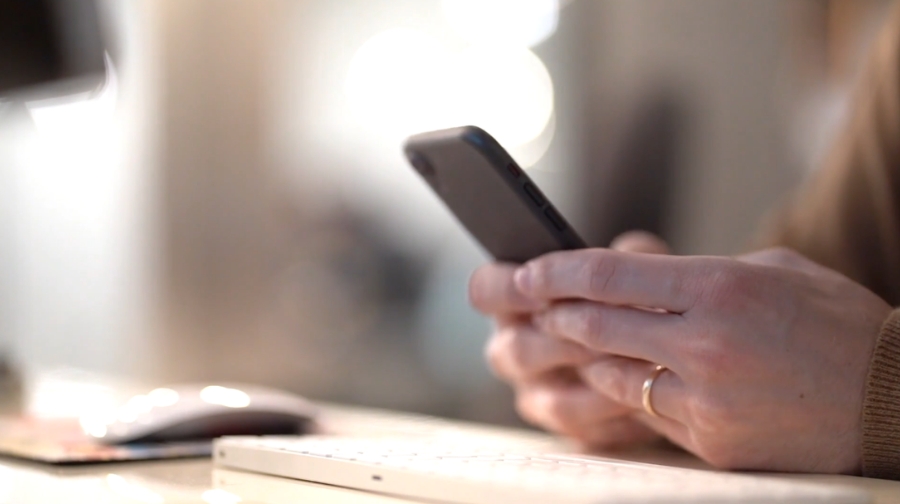 A person holds a smartphone at a desk, focusing on securing their accounts during a clean-up process