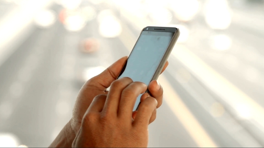A person uses a smartphone outdoors, focusing on keeping their money and identity safe