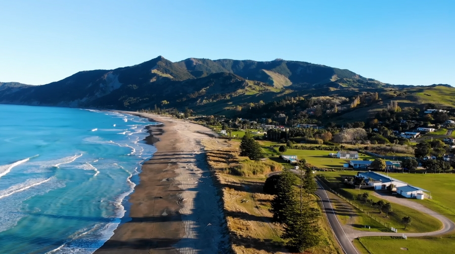 A coastal landscape in New Zealand with mountains and blue waters, highlighting its rank as one of the safest countries in the world