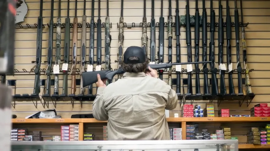 A man looks at rifles on display in a gun store, illustrating the need for tips for interpreting gun data