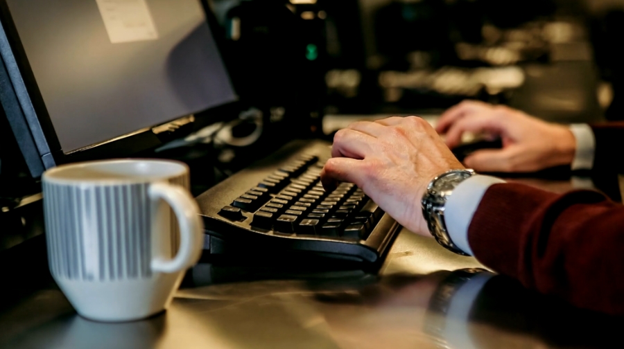 Person typing on a desktop computer where access may be blocked by a network policy or ISP