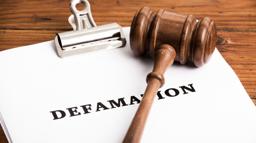 A judge’s gavel rests on a document labeled “Defamation,” symbolizing legal limits on free speech