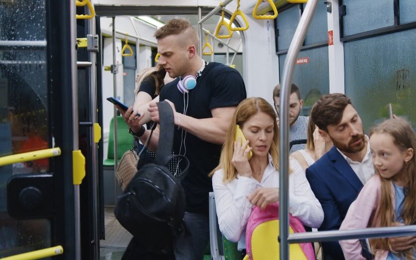 A crowded bus, with passengers focused on their phones and conversations