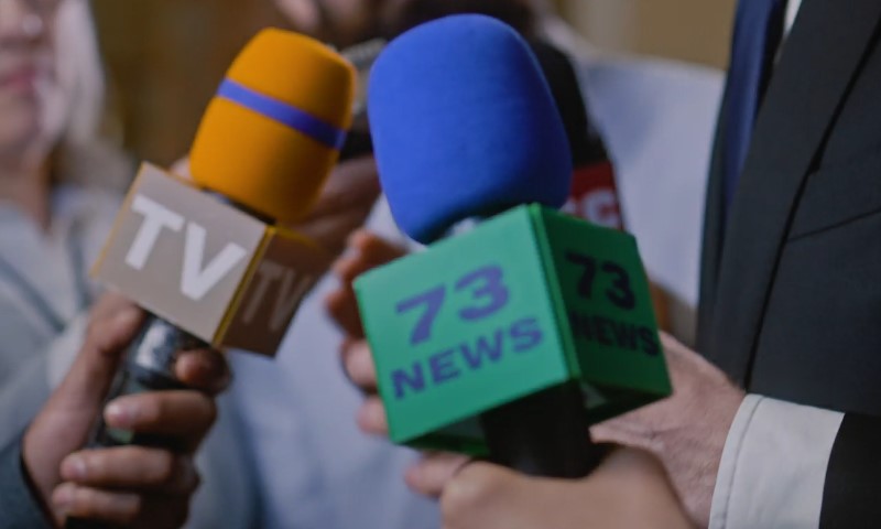 A group of people speaking to the media while holding microphones