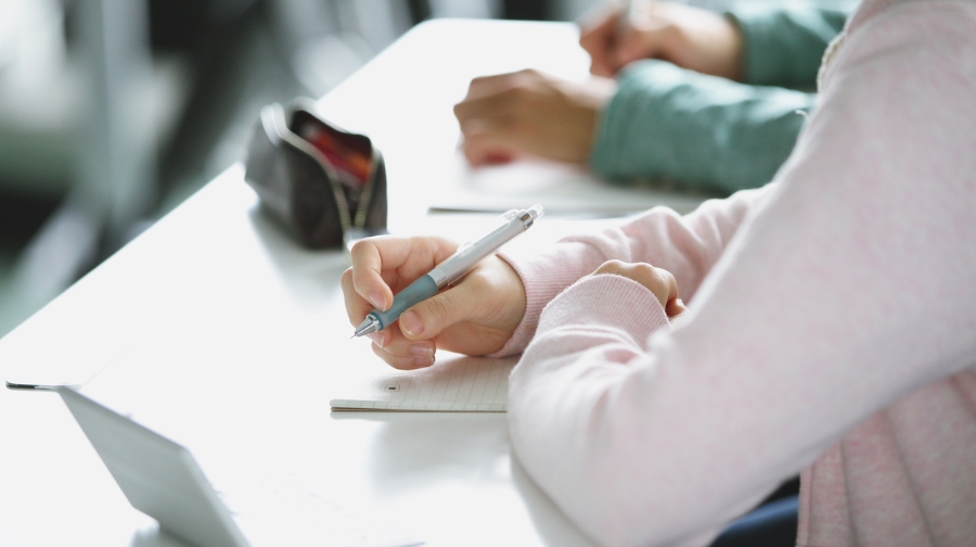 Student writing notes at a desk while organizing paperwork for loan repayment