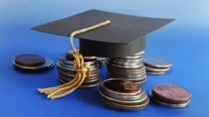Graduation cap placed on stacks of coins representing student costs and repayment plans