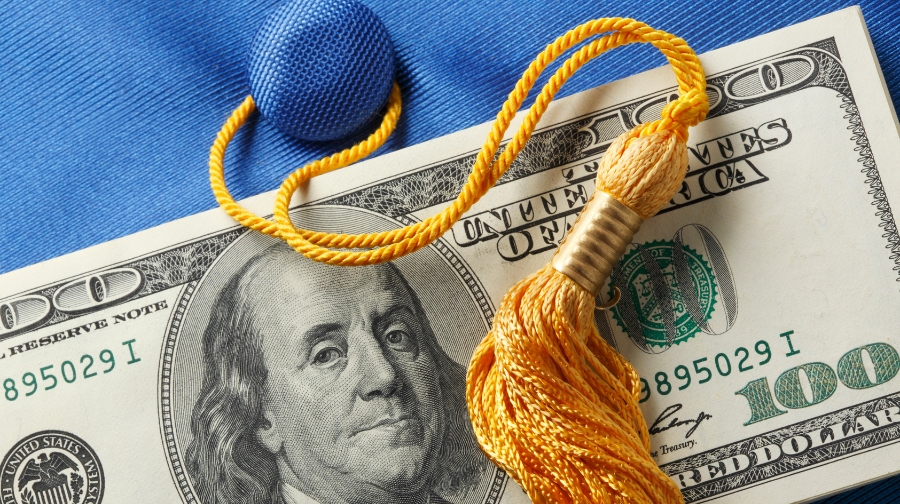 Graduation tassel placed on a hundred-dollar bill