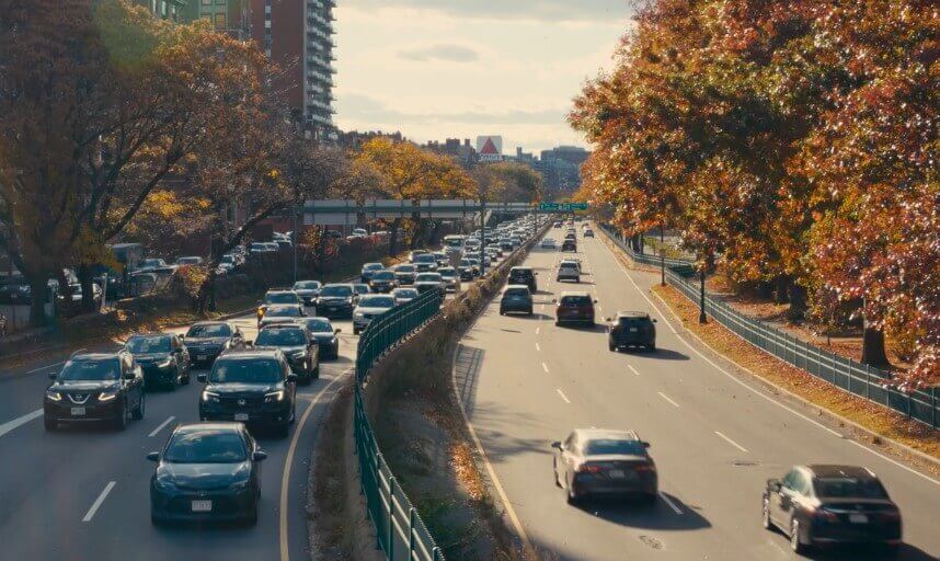 A highway choked with cars under a canopy of autumnal trees
