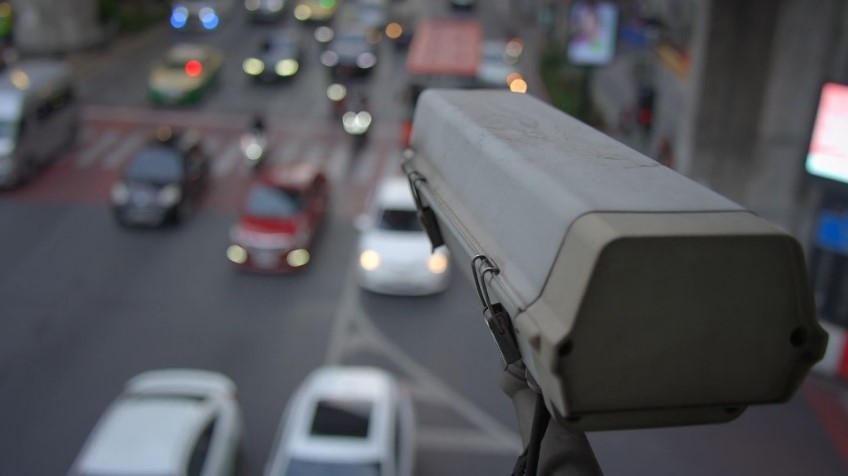 Surveillance camera overlooks a bustling street with blurred traffic lights and cars