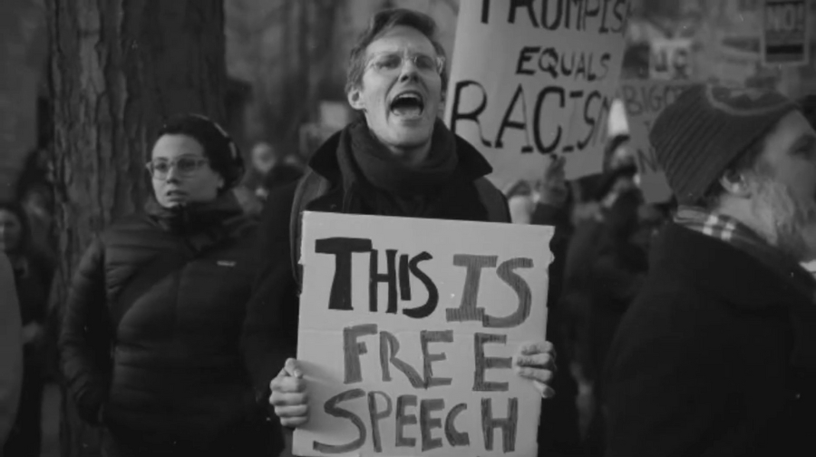 A protester holds a sign reading “This is Free Speech” during a demonstration