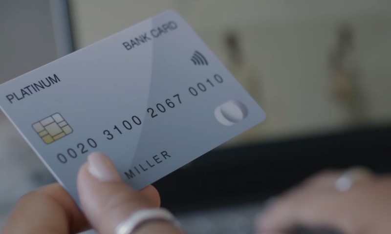 Close-up of a hand holding a silver 'Platinum' bank card