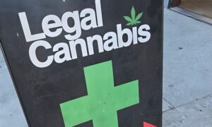 Black A-frame sign advertising "Legal Cannabis" with white lettering and a green marijuana leaf icon