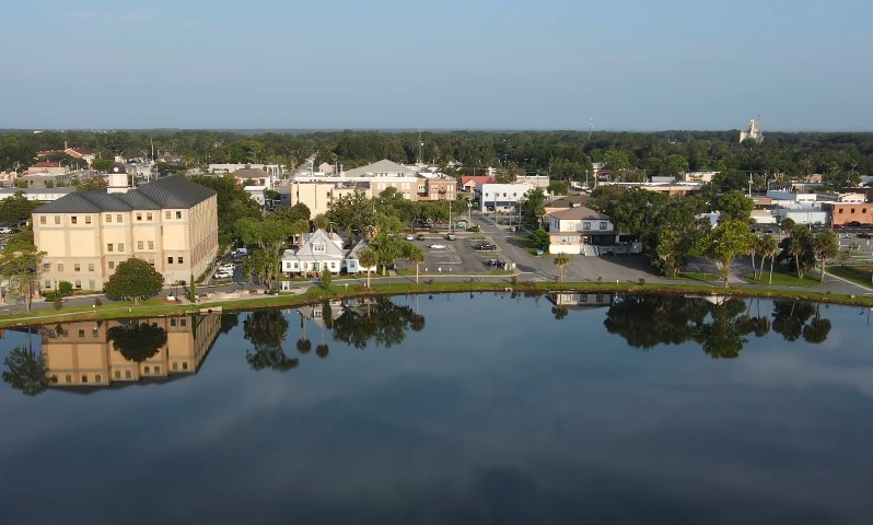 Aerial view capturing the mixed commercial and residential architecture bordering a calm body of water