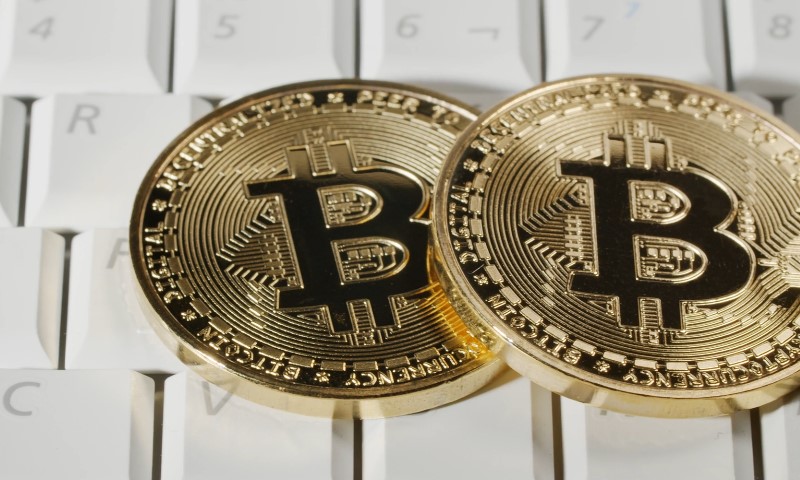 Two gold bitcoin coins resting on a computer keyboard