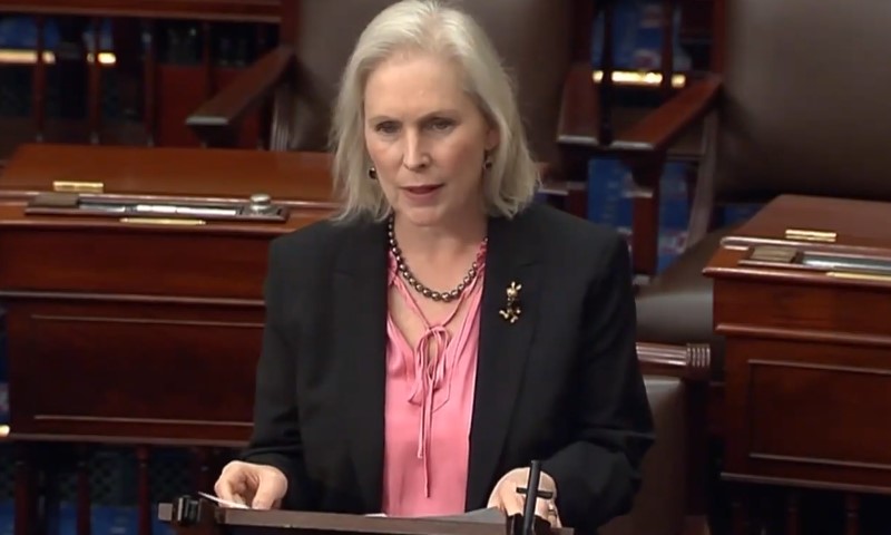 Senator Gillibrand in a suit speaks confidently at a desk