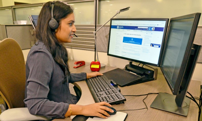 A woman wearing a headset is focused on her work at a computer