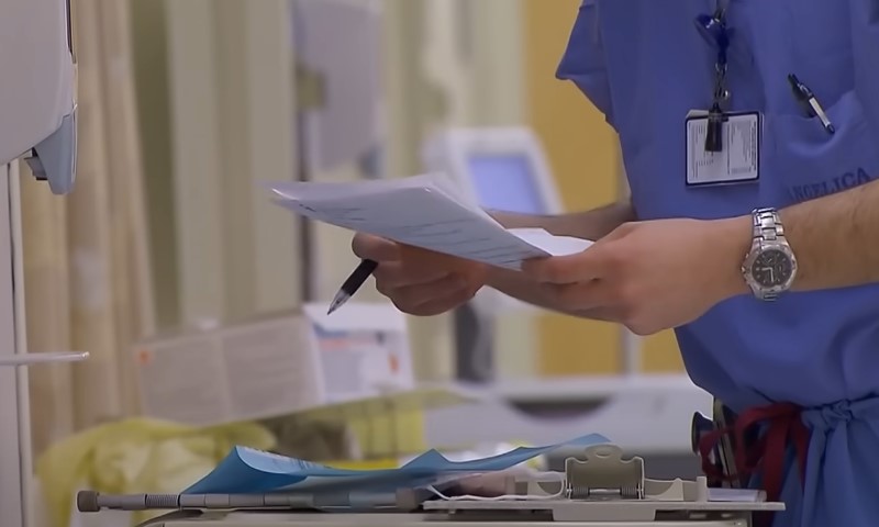 A nurse in scrubs is holding a piece of paper