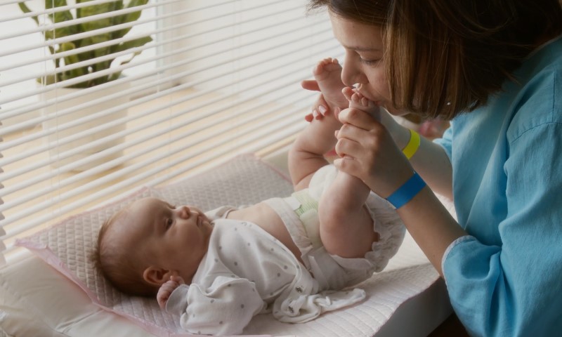 A mother gently kisses the tiny feet of a newborn baby