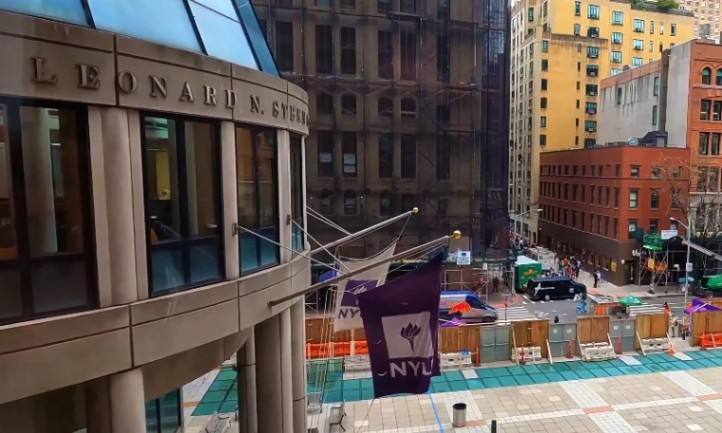 A bustling city street filled with numerous buildings, including NYU building