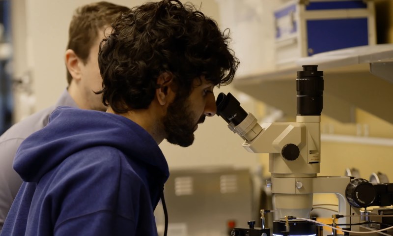 Two men examining samples through a microscope in a laboratory setting