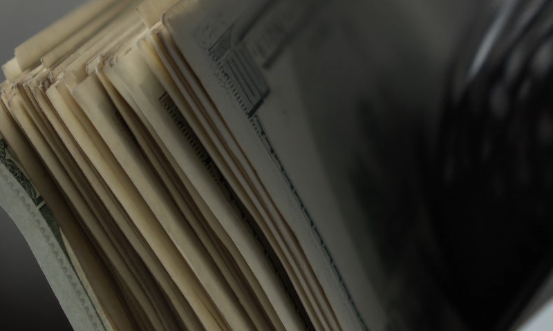 A stack of cash placed in front of a vintage black and white camera
