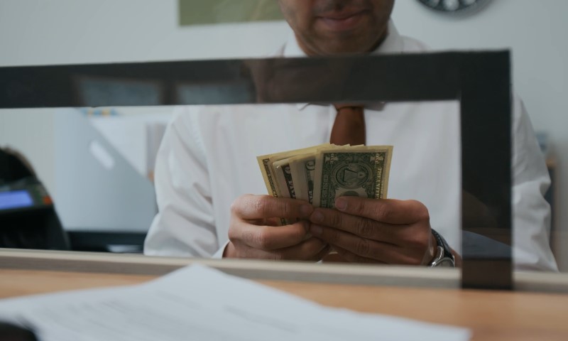 A man in a white shirt and tie is holding a stack of money
