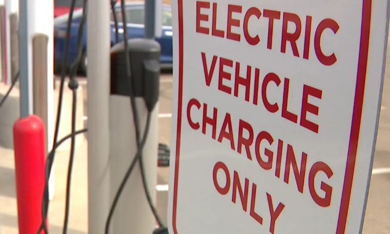 White sign with red letters saying "ELECTRIC VEHICLE CHARGING ONLY"