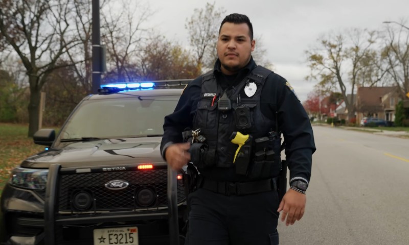 A police officer stands in front of a police car