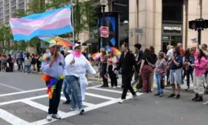 A Pride parade scene with people holding rainbow and transgender flags