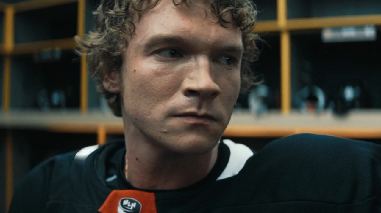 Ilya Rozanov in a black uniform looks to the side with a focused expression