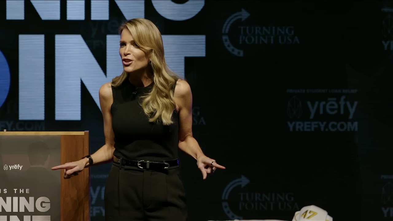 Megyn Kelly in a black sleeveless top is speaking on stage