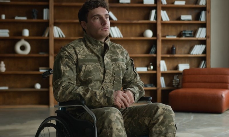 A man in military camouflage sits in a wheelchair