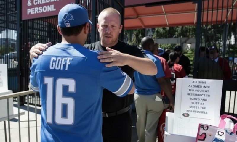 Security personnel checks a man wearing a blue football jersey with "16" and "GOFF" on the back