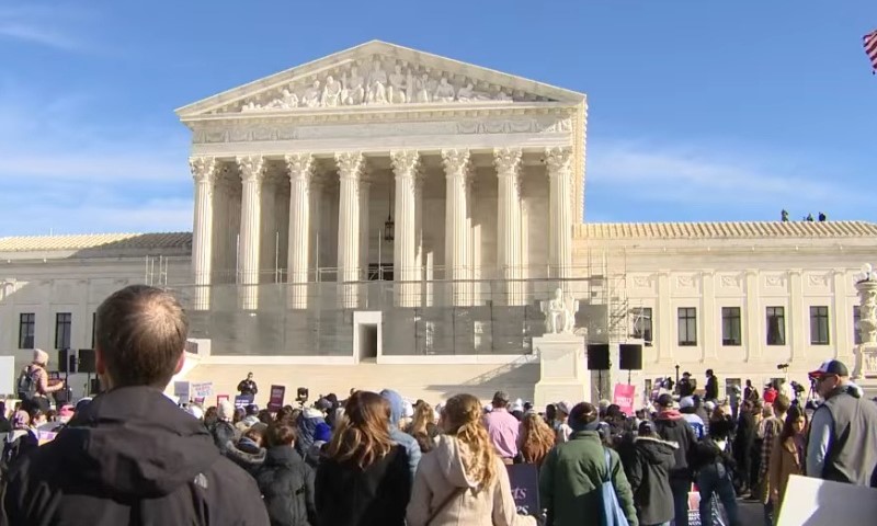 Crowd gathered outside the U.S. Supreme Court building on a sunny day