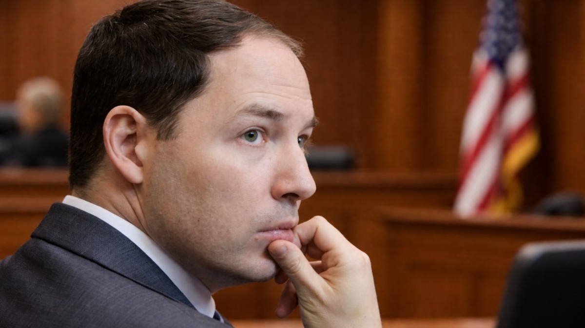 Brendan Banfield in a suit appearing thoughtful in a courtroom setting