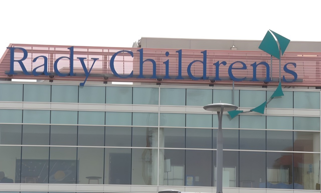 Exterior of a modern building with large glass windows, displaying the sign "Rady Children's" in blue letters above
