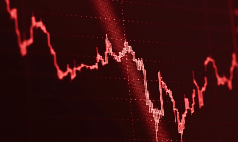 Red line graph on dark red background showing a sharp downward trend, suggesting financial loss or market decline