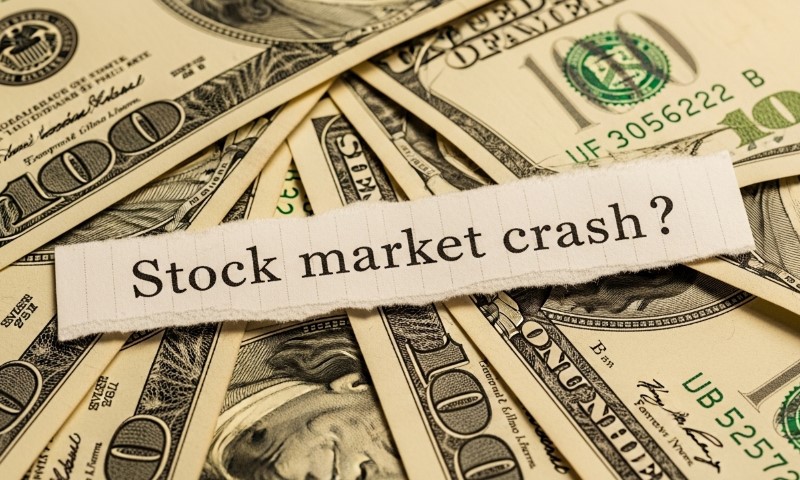 Torn paper with "Stock market crash?" on a bed of 100-dollar bills