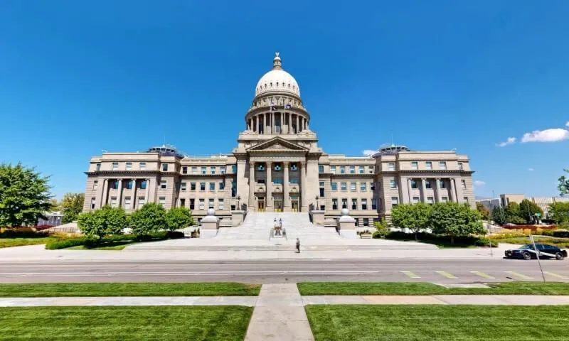 Majestic neoclassical capitol building against a clear blue sky, featuring a grand dome