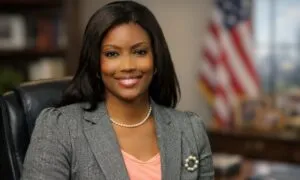 Rashida Jones looking directly at the camera with a bright, engaging smile, seated in a leather chair