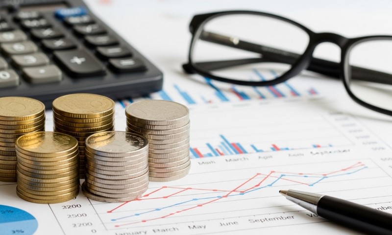 Stacks of coins on financial charts with graphs