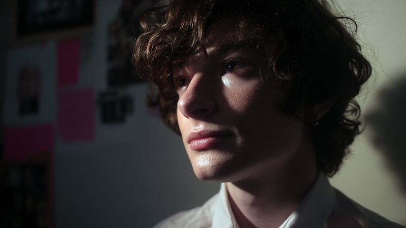 Close-up of a trans person in low light, representing personal financial responsibility after surgery funding