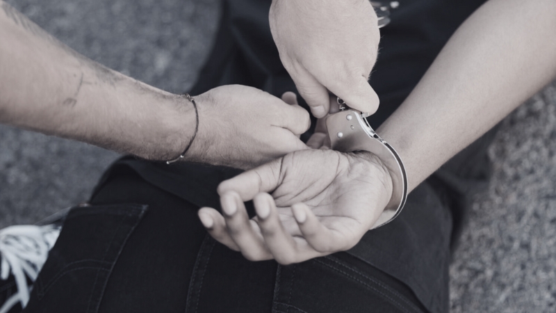 Officer placing handcuffs on a person’s wrists during an arrest